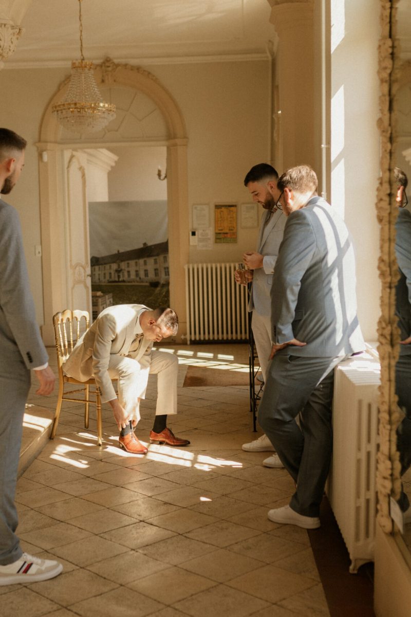 le marié se prépare au milieu de ses proches dans le hall du chateau d'art sur meurthe