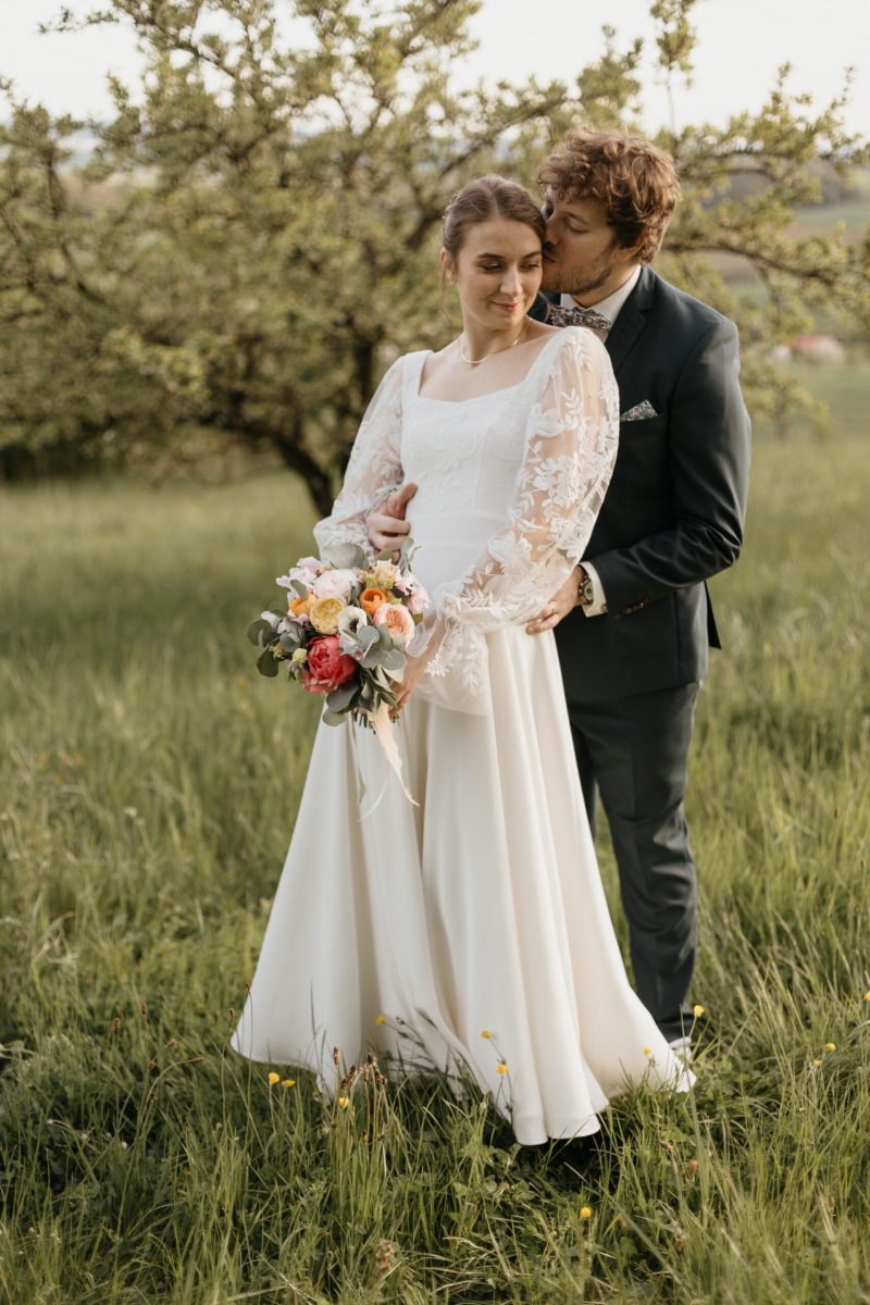 Couple de mariés dans un verger bouquet de fleurs coloré